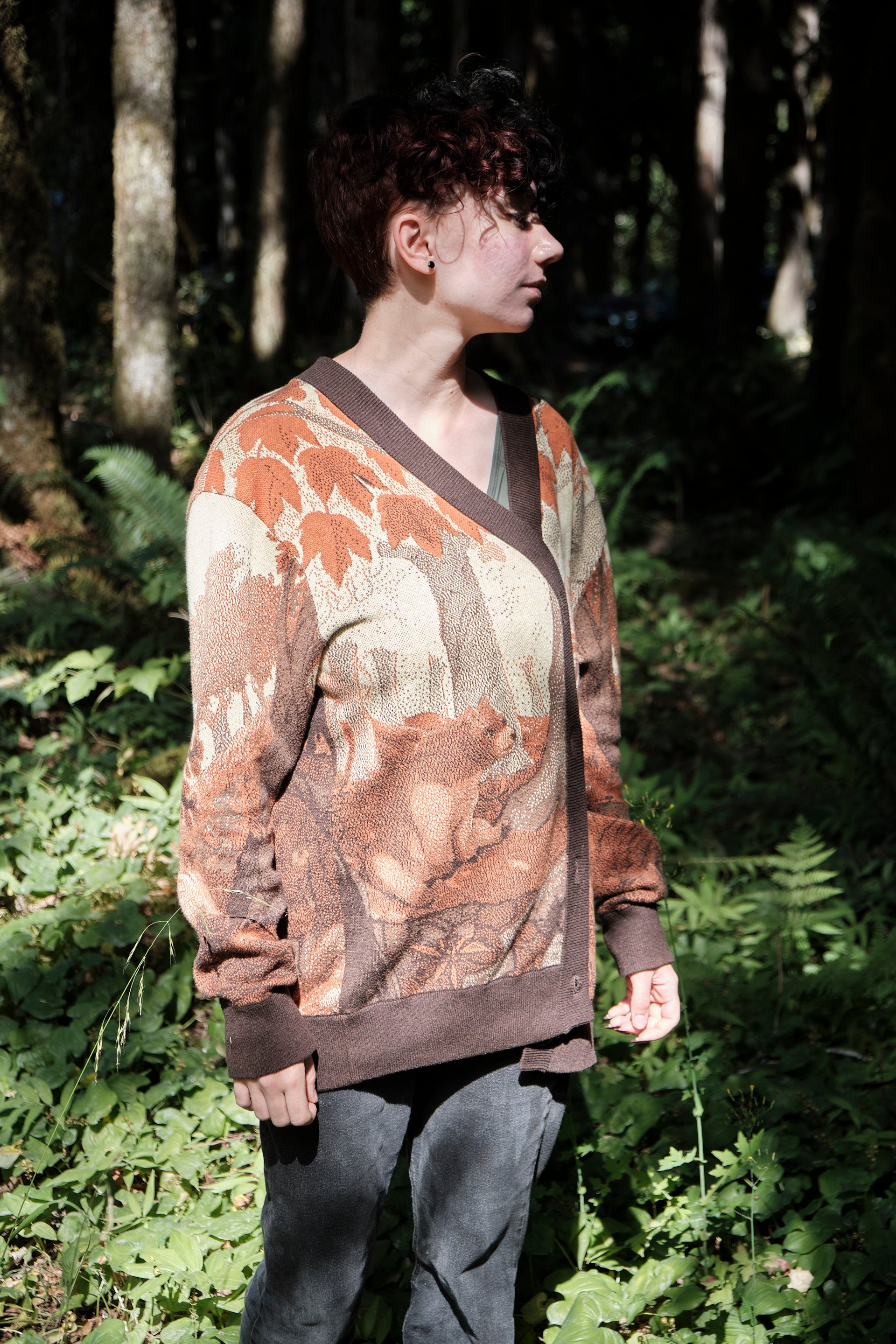 Person wearing a patterned sweater standing in a forest