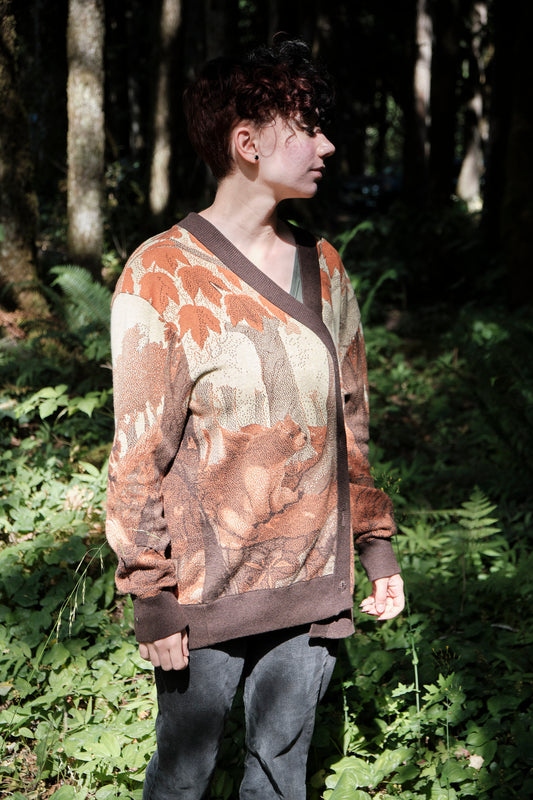 Person wearing a patterned sweater standing in a forest